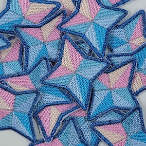 May include: A pile of blue, pink, and white star-shaped fabric patches. The stars are made of a quilted fabric and have a blue outline.