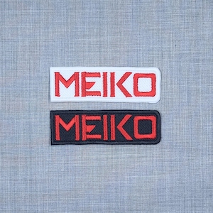 May include: Two embroidered patches with the word "MEIKO" in red lettering. The top patch is white with red lettering. The bottom patch is black with red lettering.