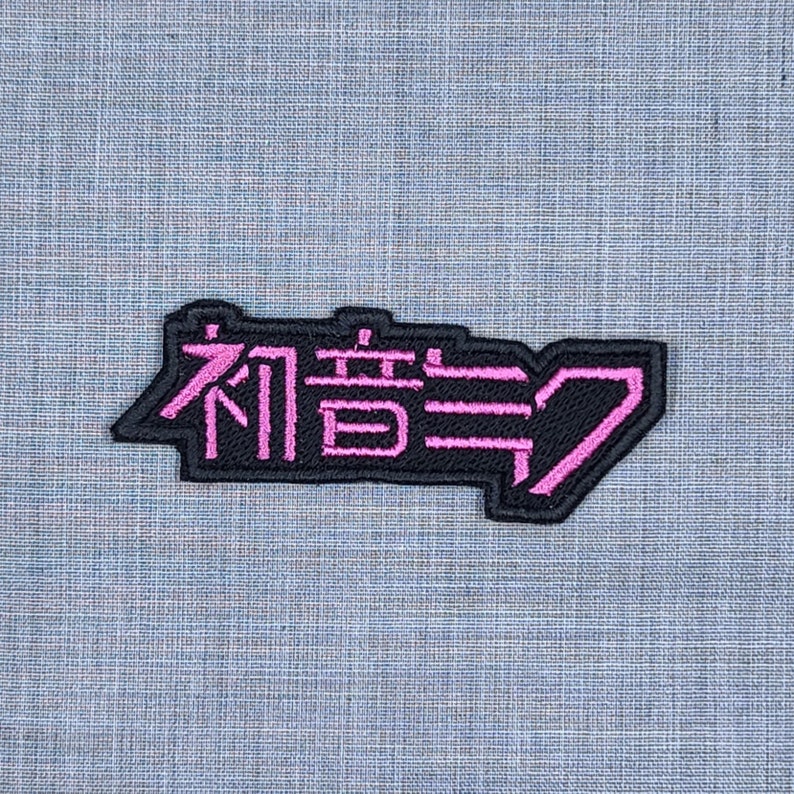 May include: Black and pink embroidered patch with the Japanese text "有言実行" which translates to "Walk the Talk".