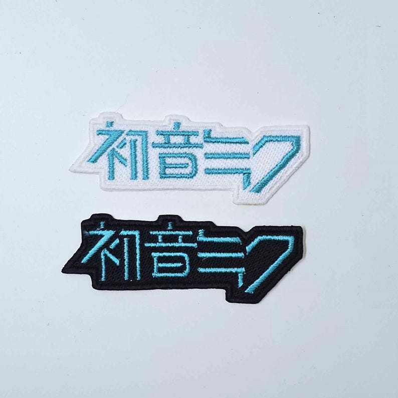 May include: Two embroidered patches with the Japanese text "有言実行" in blue on a white background and black background.
