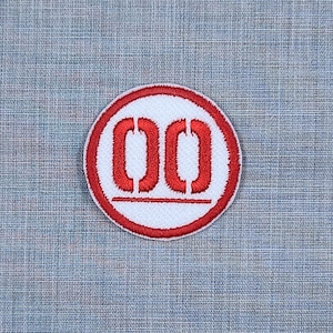 Puede incluir: Parche bordado rojo y blanco con el n&uacute;mero "00" en un c&iacute;rculo.