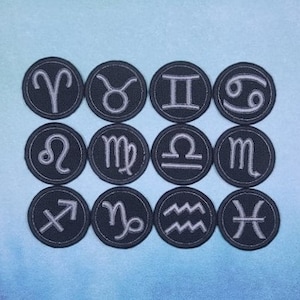 May include: Twelve black and white embroidered iron-on patches featuring the astrological zodiac signs. The signs are in a circle with a silver outline.