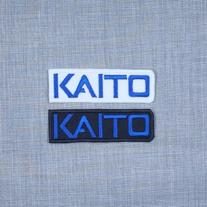 May include: Two embroidered patches with the name "KAITO" in blue lettering. The top patch is white and the bottom patch is black.
