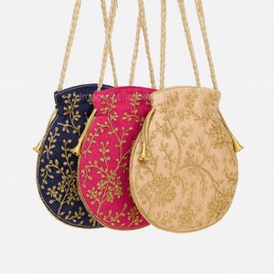 Puede incluir: Tres bolsas bordadas con cordón en azul marino, fucsia y beige. Cada bolsa presenta un diseño floral dorado y una borla dorada. Las bolsas tienen cordones dorados y cuelgan sobre un fondo blanco.