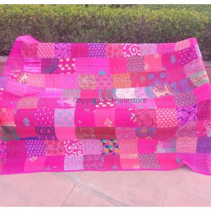 Può includere: Una trapunta kantha rosa con un design a patchwork. La trapunta è realizzata con diversi tessuti in tonalità di rosa, viola e blu. La trapunta è cucita a mano e ha un aspetto unico e rustico.
