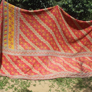May include: A red and yellow kantha quilt with a geometric pattern. The quilt is made of cotton and is hand-stitched. It is a traditional Indian textile.
