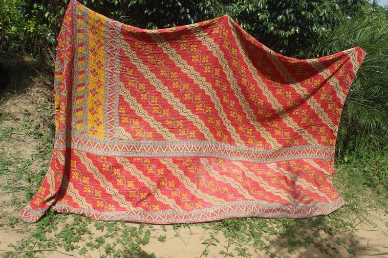 May include: A red and yellow kantha quilt with a geometric pattern. The quilt is made of cotton and is hand-stitched. It is a traditional Indian textile.