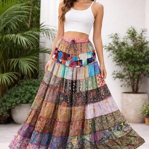 Puede incluir: Falda larga escalonada con diseño de patchwork en varios colores, incluyendo azul, rosa, verde y morado. La falda tiene cintura con cordón y una silueta fluida. La modelo lleva un top corto blanco.