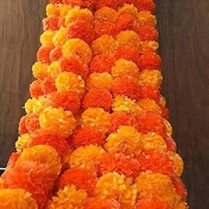 May include: A long garland of orange and yellow marigold flowers. The garland is made of artificial flowers and is perfect for decorating for a special occasion.