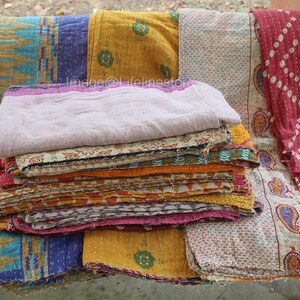 May include: A stack of colourful kantha quilts with various patterns and designs. The quilts are made of cotton and are hand-stitched. They are perfect for adding a touch of bohemian style to any home.