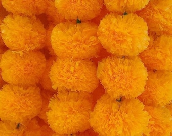 Könnte beinhalten: Nahaufnahme einer Reihe von leuchtend orangefarbenen Ringelblumen-Girlanden. Die Girlanden sind aus Papier und eignen sich perfekt zum Dekorieren für ein Fest oder eine Feier.