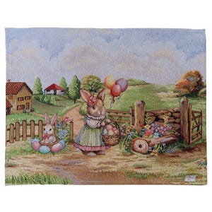 Könnte beinhalten: Ein Wandteppich, der eine Osterszene mit zwei Hasen darstellt. Ein Hase trägt einen Korb mit Eiern und Luftballons, der andere sitzt in einem Nest aus Eiern. Der Hintergrund zeigt eine ländliche Landschaft mit Häusern, Bäumen und einem Holzzaun.