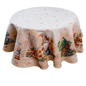 May include: Round tablecloth with a whimsical autumn design. The cream-colored cloth features illustrations of gnomes, pumpkins, sunflowers, and woodland scenes. The edges are scalloped, and the top has a subtle leaf pattern.