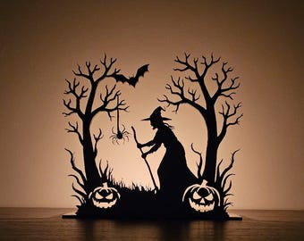 Puede incluir: Silueta negra con temática de Halloween que presenta una bruja con una escoba, calabazas, árboles, un murciélago y una araña. El diseño está recortado de un material oscuro, creando una escena espeluznante. Es probable que sea un artículo decorativo.