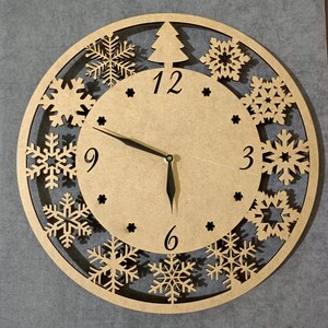 May include: A wooden clock with a snowflake design. The clock face has black hands and black numbers. The clock is 30 cm in diameter.