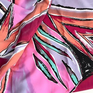 May include: A pink, purple, orange, and teal fabric with a geometric pattern of abstract leaves. The fabric is soft and flowing.