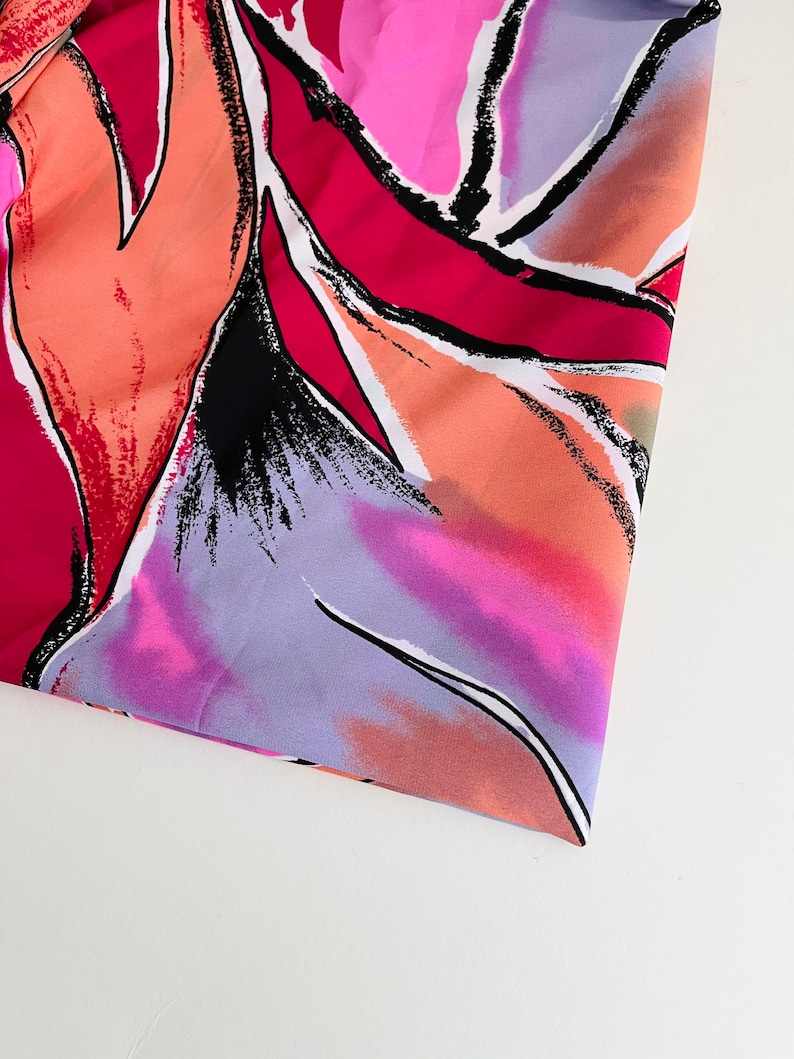 May include: Abstract floral print fabric in shades of pink, orange, purple, and black. The fabric has a soft, flowing texture.