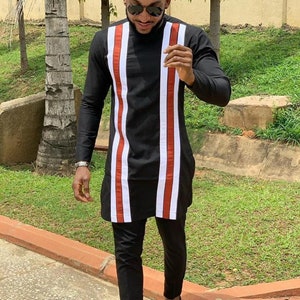 May include: A black long-sleeved shirt with red and white vertical stripes. The shirt has a high neck and long sleeves. The man is wearing black pants and black shoes.