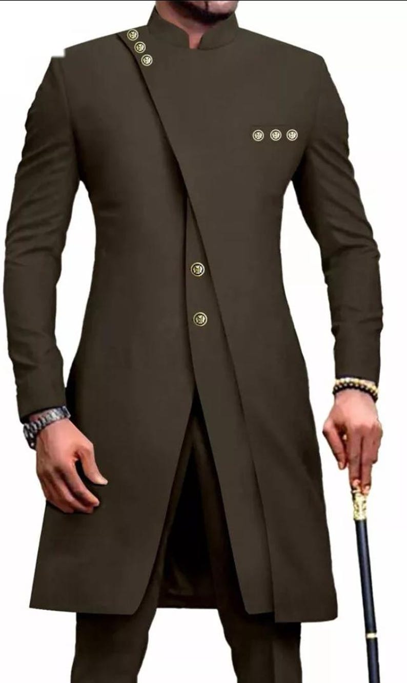 May include: A long-sleeved brown suit jacket with a mandarin collar and gold buttons. The jacket has a unique asymmetrical design with a long, flowing front panel.