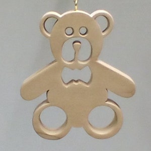 May include: A wooden teddy bear ornament with a bow tie. The bear is light brown and has a simple design.