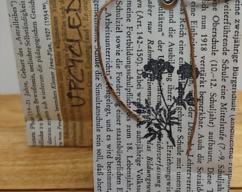 Small hand-folded upcycled paper bags made from book pages, with eyelets in silver or gold and ribbons, set with 3 different flower motifs