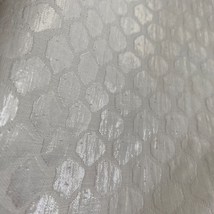 Puede incluir: Tela blanca con un sutil patr&oacute;n en relieve de peque&ntilde;os c&iacute;rculos. La tela tiene una superficie ligeramente texturizada.
