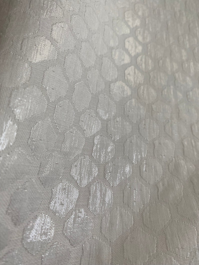 Puede incluir: Tela blanca con un sutil patr&oacute;n en relieve de peque&ntilde;os c&iacute;rculos. La tela tiene una superficie ligeramente texturizada.
