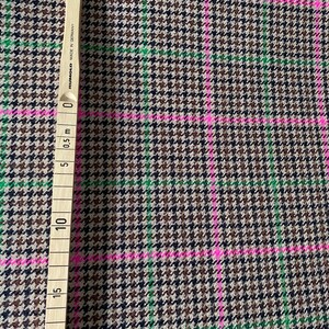May include: Brown, black, and green houndstooth fabric with pink and green stripes. The fabric is measured with a ruler that shows 20 inches.