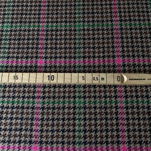 May include: Brown, black, and green houndstooth fabric with pink and green stripes. A ruler is visible at the bottom of the image with markings in centimeters and inches.