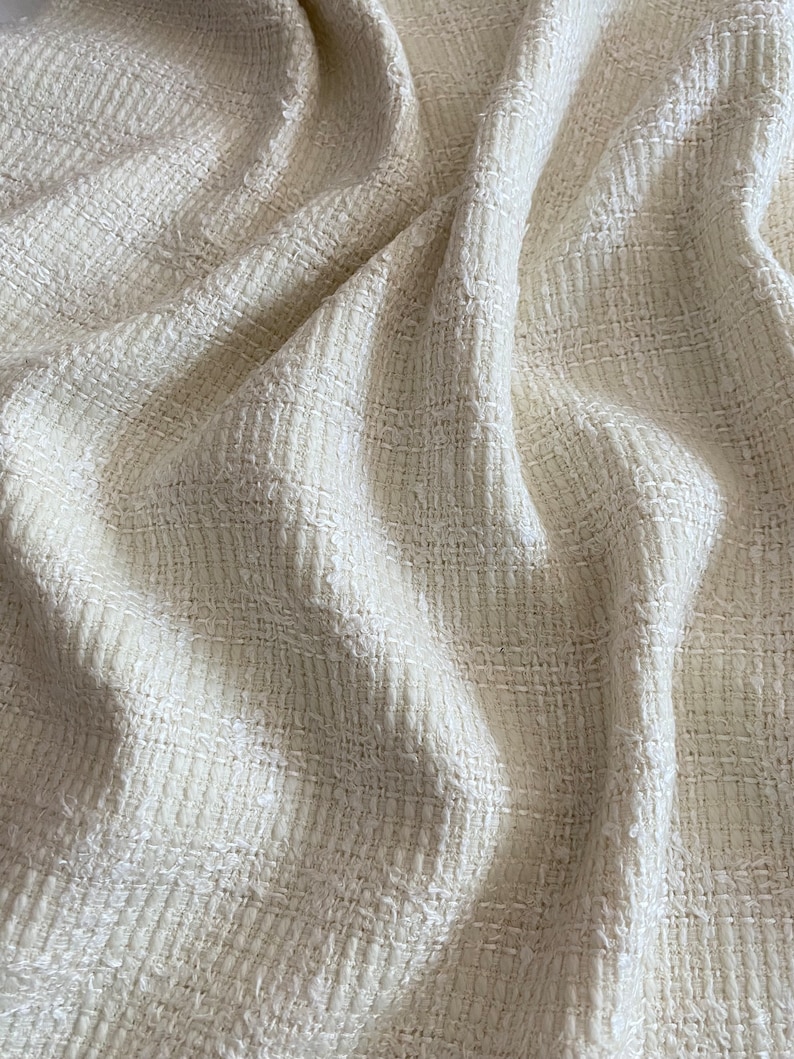 May include: Close-up of a white textured fabric with a woven pattern. The fabric is soft and has a slightly rough texture.