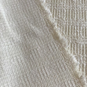 May include: Two pieces of white fabric with different textures. One piece has a smooth, woven texture, while the other has a more textured, woven look with a frayed edge.