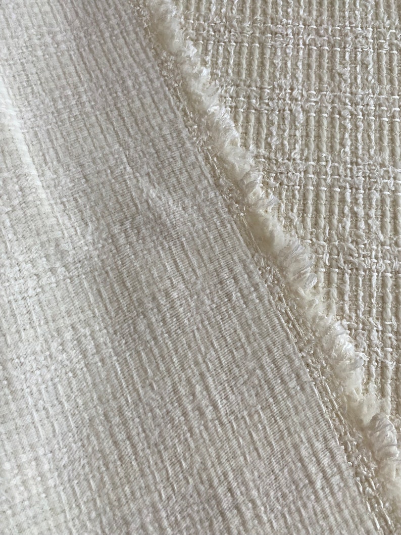 May include: Two pieces of white fabric with different textures. One piece has a smooth, woven texture, while the other has a more textured, woven look with a frayed edge.