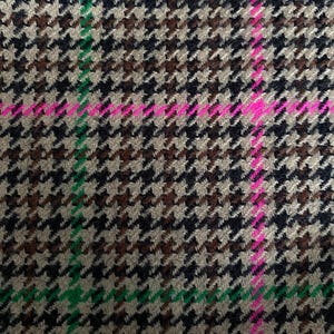 May include: A close-up of a brown, black, and white houndstooth fabric with a green and pink plaid pattern.