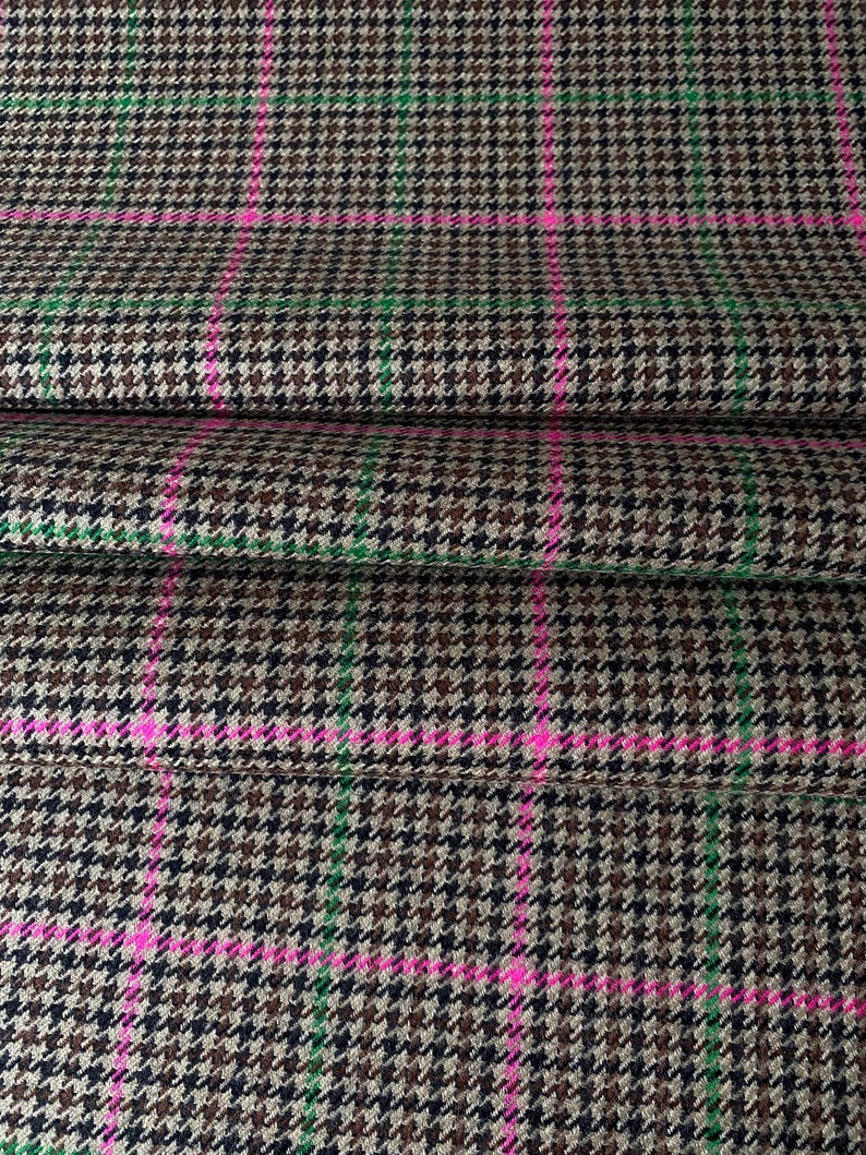 May include: Brown, black, and green houndstooth fabric with pink stripes. The fabric has a woven texture.