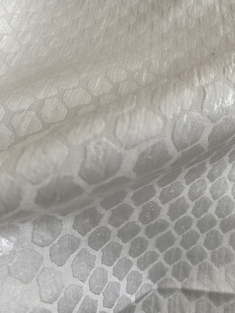 Puede incluir: Tela blanca con un sutil patr&oacute;n en relieve de formas hexagonales repetidas.