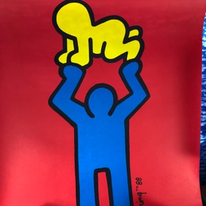 May include: A blue stick figure with outstretched arms holding a yellow stick figure above its head. The background is red. The text "88 TM" is in the bottom right corner.