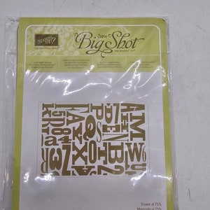 May include: A gold-colored alphabet die cut for use with a Big Shot die-cutting machine. The die cut is shown at 75% of its actual size.