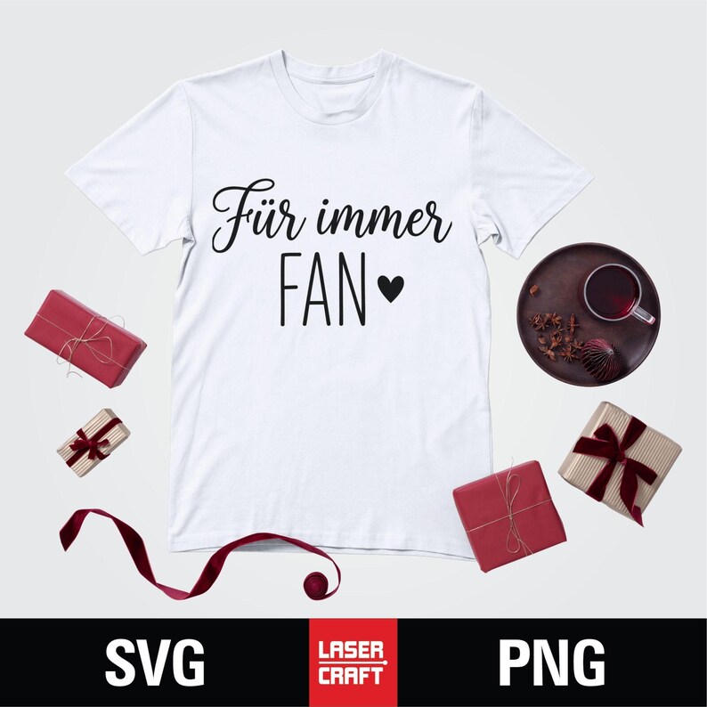May include: White t-shirt with the text "F&uuml;r immer FAN" in black script and a heart symbol. The shirt is surrounded by wrapped gifts, a tray with a drink, and the words "SVG" and "PNG" at the bottom.