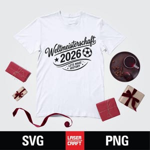 May include: White t-shirt with the text "Weltmeisterschaft 2026" and a soccer ball graphic. The phrase "Lets Make History" is also included. The shirt is surrounded by wrapped gifts and a decorative plate.