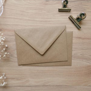 Puede incluir: Un sobre marr&oacute;n con una superficie texturizada. El sobre est&aacute; doblado por la mitad y tiene una solapa en la parte superior.