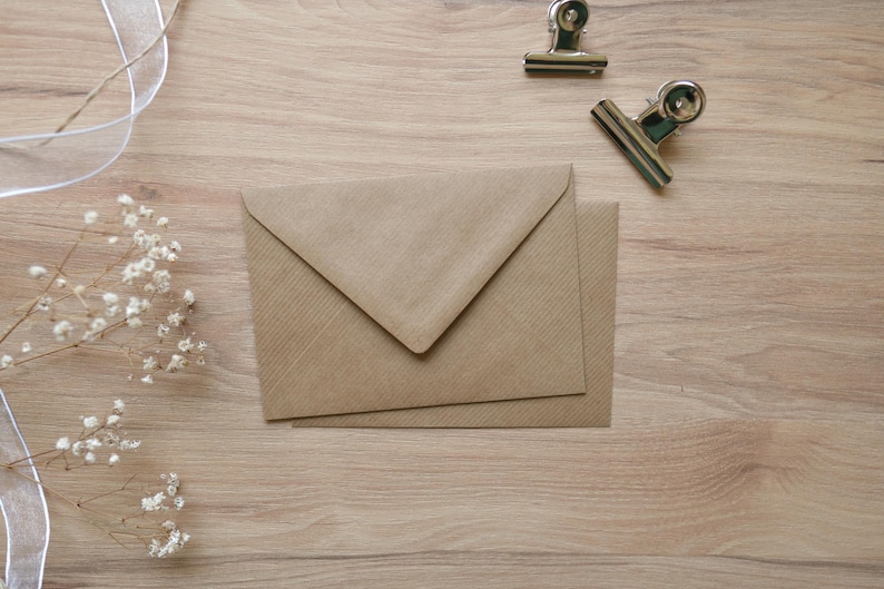 Puede incluir: Un sobre marr&oacute;n con una superficie texturizada. El sobre est&aacute; doblado por la mitad y tiene una solapa en la parte superior.