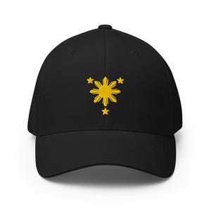 May include: Black baseball cap with a yellow embroidered design featuring a sunburst and three stars. The cap has a curved brim and a structured fit, suitable for various head sizes.