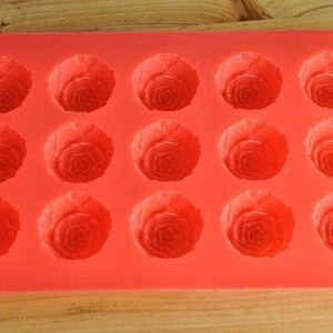 May include: Red silicone mold with 15 cavities shaped like roses. The mold is designed for making chocolate, candy, or soap.