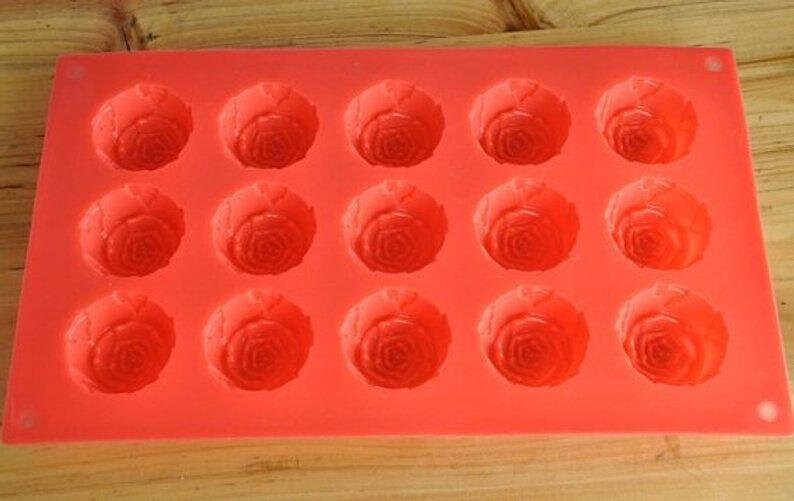 May include: Red silicone mold with 15 cavities shaped like roses. The mold is designed for making chocolate, candy, or soap.
