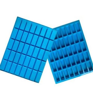 Peut inclure: Deux moules en silicone bleu avec des cavités rectangulaires. Les moules sont conçus pour faire des barres de chocolat ou d'autres friandises.