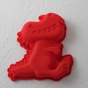 May include: Red silicone dinosaur-shaped mold for baking or crafting.