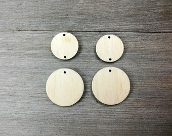 May include: Four unfinished, round wooden circles with a hole in the center. The circles are arranged in two rows of two on a woodgrain background.