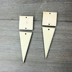 May include: Two sets of unfinished wooden craft shapes. Each set includes a square and a triangle. The shapes have holes in the top for hanging.