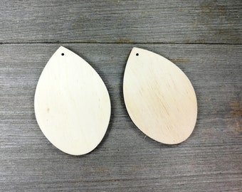 May include: Two unfinished wooden teardrop shapes with a hole at the top. The shapes are light brown and have a smooth surface.