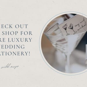 May include: A martini glass with wedding stationery, including a card with cocktail illustrations and the names "rong and michael." The text reads "CHECK OUT THE SHOP FOR MORE LUXURY WEDDING STATIONERY!" in navy blue.